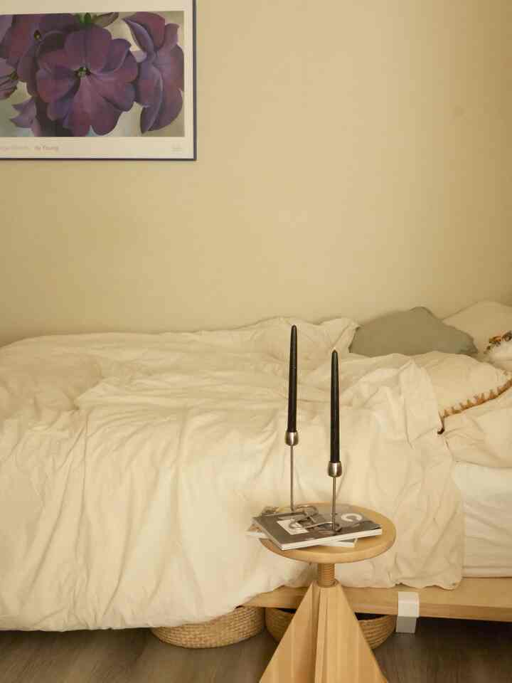 Warm beige bedroom with natural wood stool featuring black candlesticks, creating a cozy atmosphere