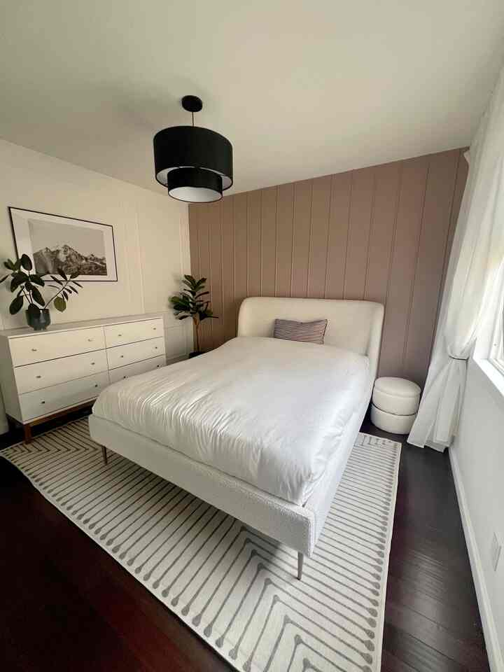 Modern bedroom with beige tone panel wall and white furniture arranged in a bright space