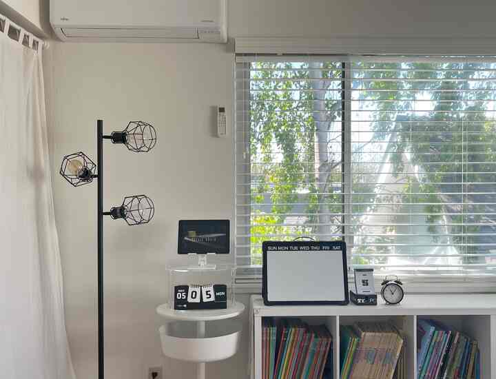 Modern home office space in white and black tones featuring a floor lamp and tidy bookshelf with a bright, organized atmosphere