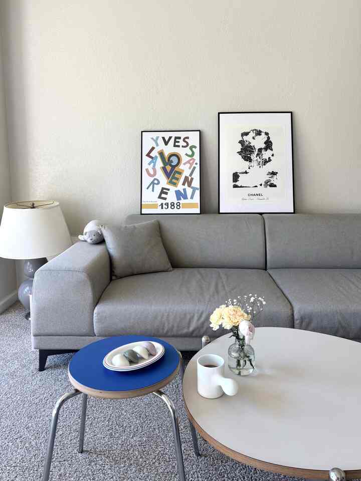 A simple modern living room featuring a gray sofa and a blue stool with minimalist decor