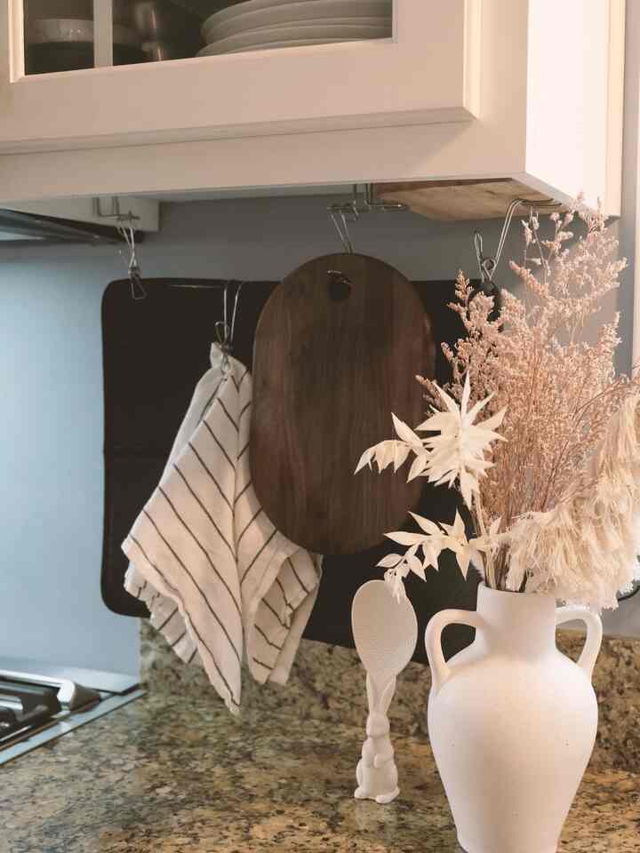 Natural-toned kitchen featuring a cutting board, kitchen towel, vase with dried flowers, creating a cozy atmosphere