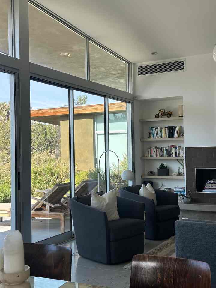 Natural modern living room with white walls and large windows, featuring black armchairs and a fireplace in a cozy setting