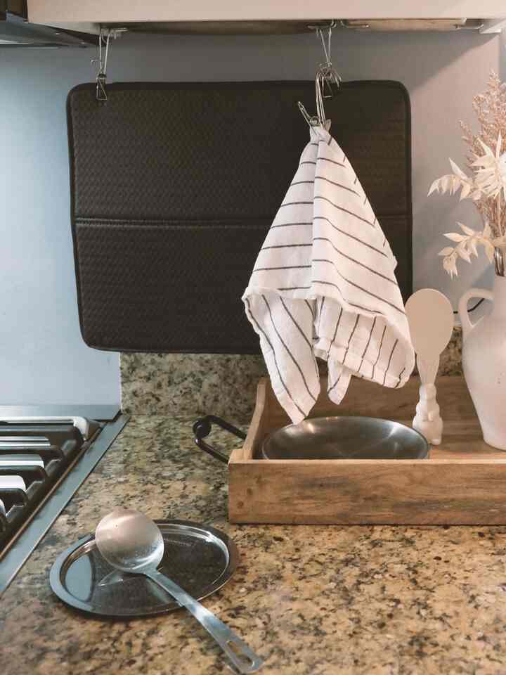 Brown marble countertop kitchen space featuring white striped kitchen towels and wooden tray with a warm atmosphere