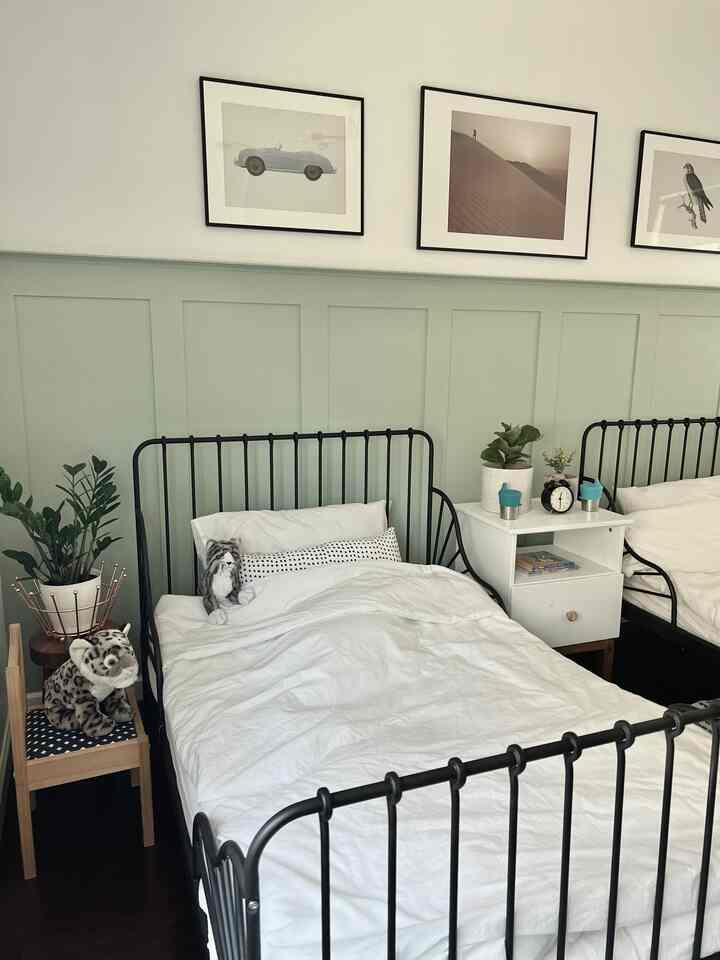 White and black toned kids' room featuring two beds, nightstand, and plants in a clean layout