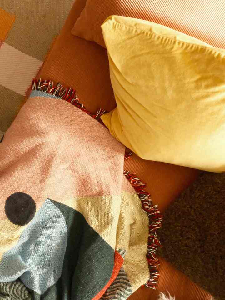 Beige and brown toned living room area featuring cushions and a blanket creating a cozy atmosphere