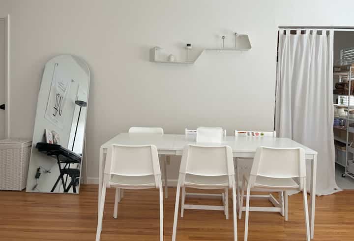 White-toned dining room featuring a white dining table and chairs centrally arranged in a simple, clean space