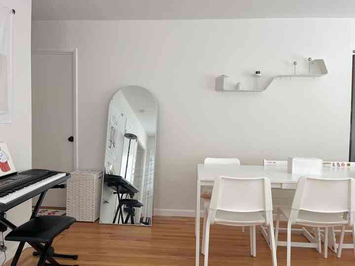 A white and wood tone dining room featuring simple and minimal furniture layout