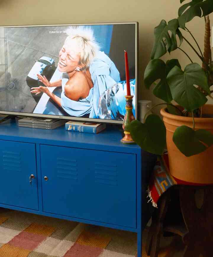 Natural beige-walled living room featuring a vibrant blue cabinet and large potted plant with stylish decor