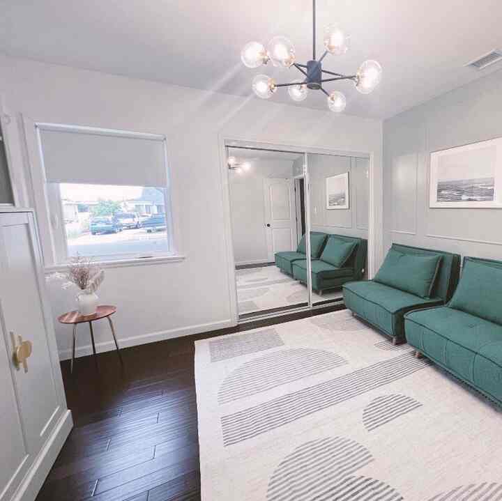 Minimal living room with soft white-tone walls and deep green sofa beds arranged along one side