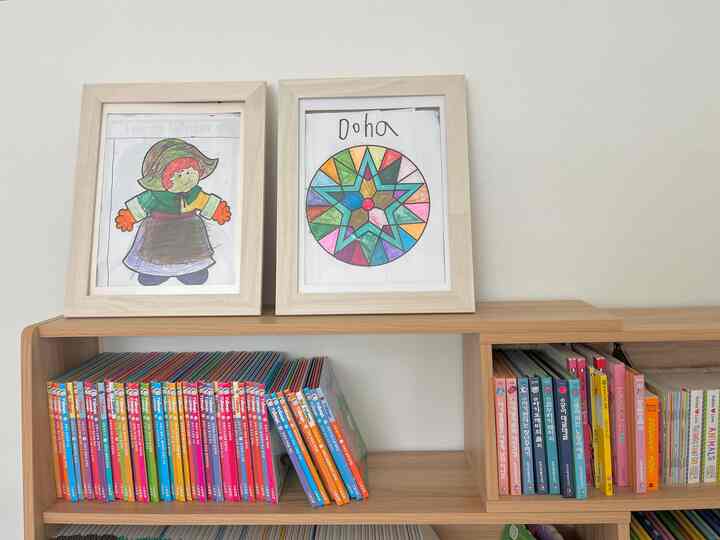 Natural wood tone shelf with colorful kids' books against white wall background in a children's space