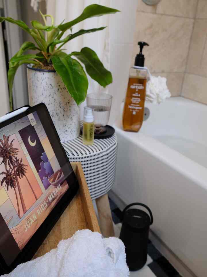 Black and white toned bathroom space featuring a round stool and green plant with a cozy and modern atmosphere