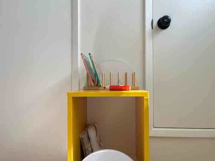 Yellow-toned kids' room with a bright yellow nightstand and children's books organized neatly