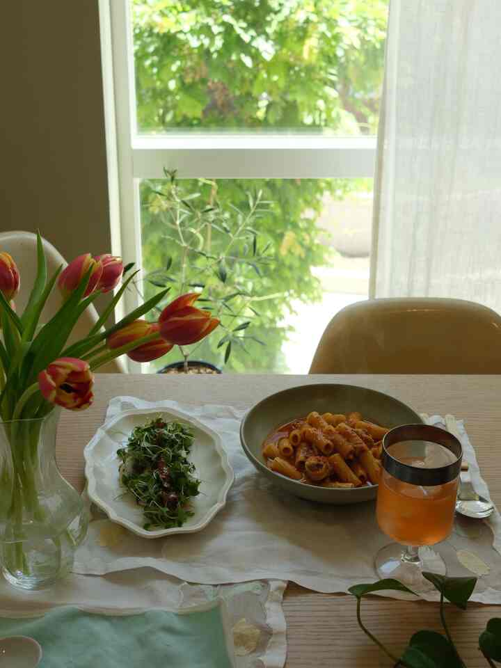 Natural cafe style dining room with yellow tulips and wooden dining table near a window showing green plants outside