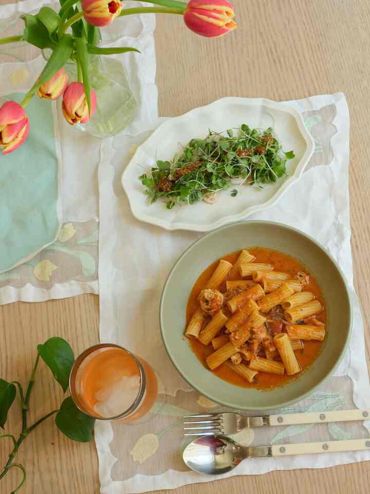 Beige and natural-tone dining table with vintage embroidered tablecloth and plates in a casual lunch setting