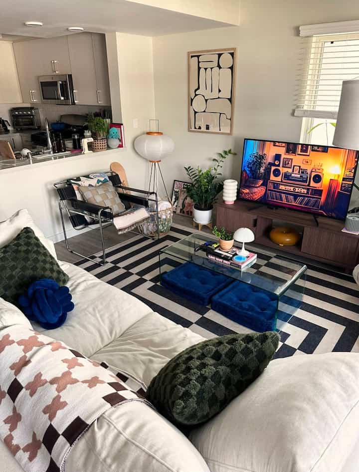White and navy-toned living room and kitchen featuring modern furniture and plants with a cozy atmosphere