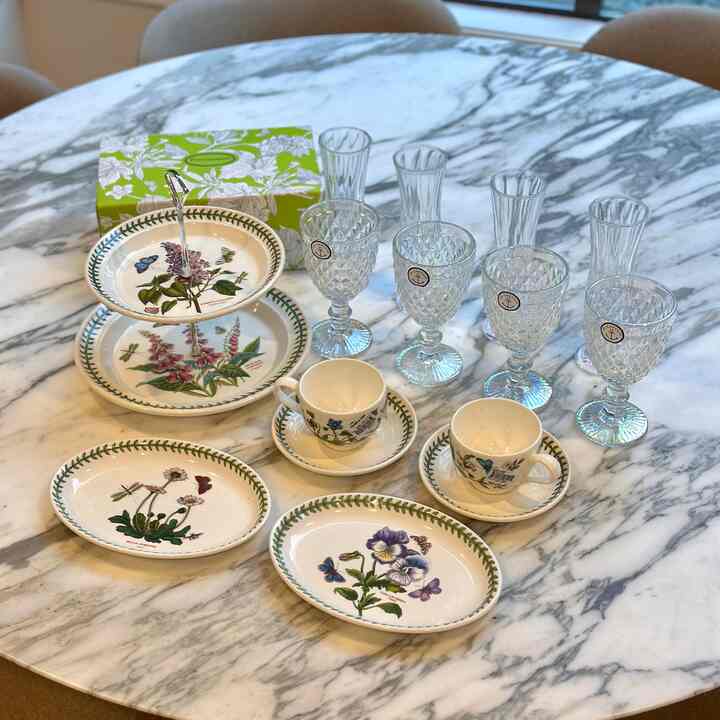 Mid-century modern dining room with white marble dining table featuring plates, teacups, and clear glasses