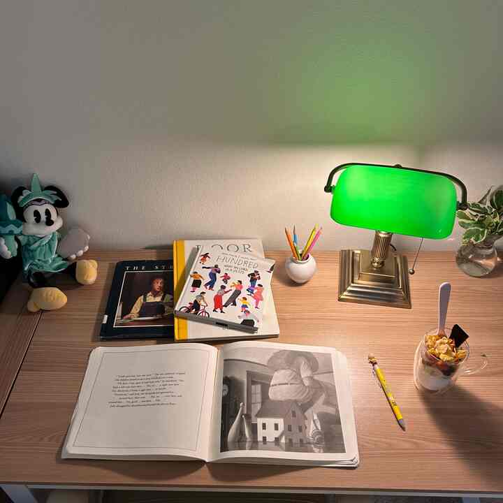 Natural color home office featuring wooden desk with books and green table lamp, creating a cozy atmosphere