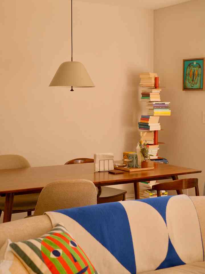 Beige and wood tone living and dining room featuring a blue throw and cushions, creating a simple and natural ambiance