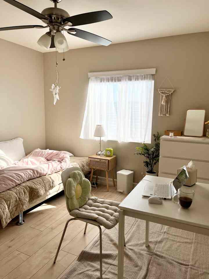 Natural-tone bedroom with beige and wood tones featuring a bed and desk in a cozy, lived-in atmosphere
