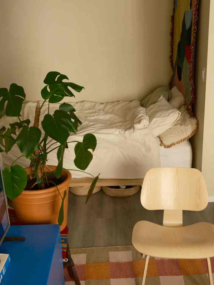 Beige-toned bedroom featuring a made bed and natural wood chair with a cozy atmosphere