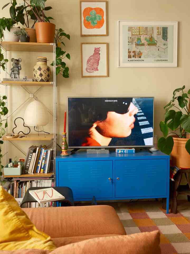 Cozy living room with warm beige walls, brown sofa, and a blue TV stand creating a harmonious space