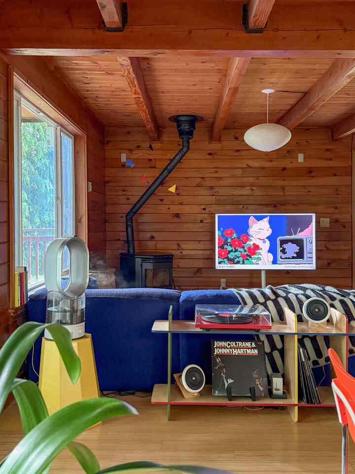 Brown wood-tone walls and ceiling living room featuring a central blue sofa and record player, creating a cozy and casual atmosphere
