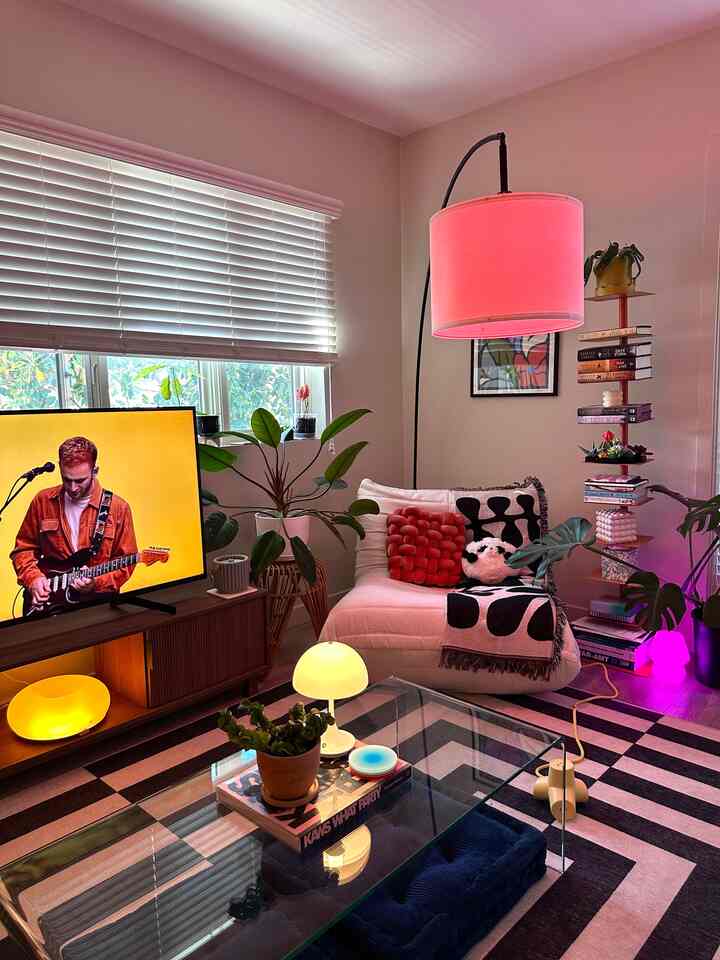 Light gray toned living room featuring white sofa, pink arc floor lamp, and colorful lighting creating a cozy atmosphere