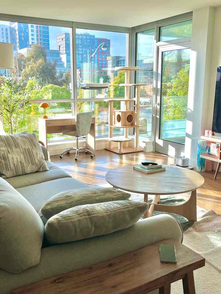 Wood tone and gray living room featuring a sofa, round coffee table, and tall cat tower with a simple, well-lit atmosphere