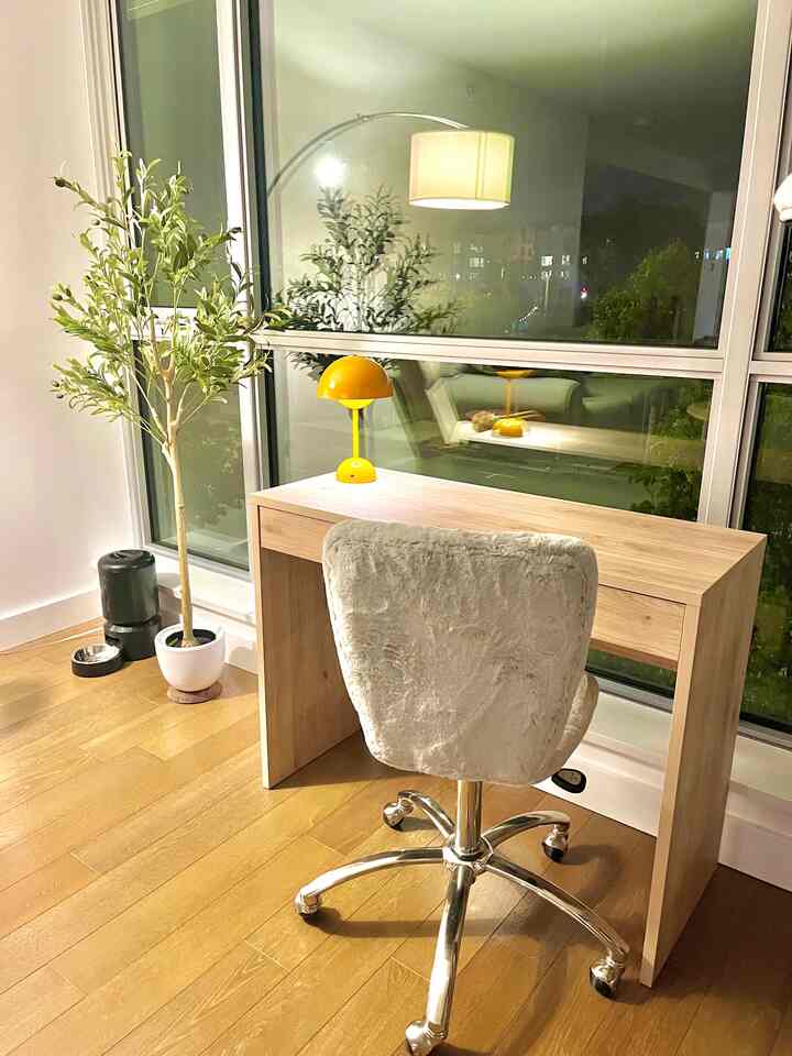 Natural wood tone living room featuring a simple home office setup with yellow table lamp accent