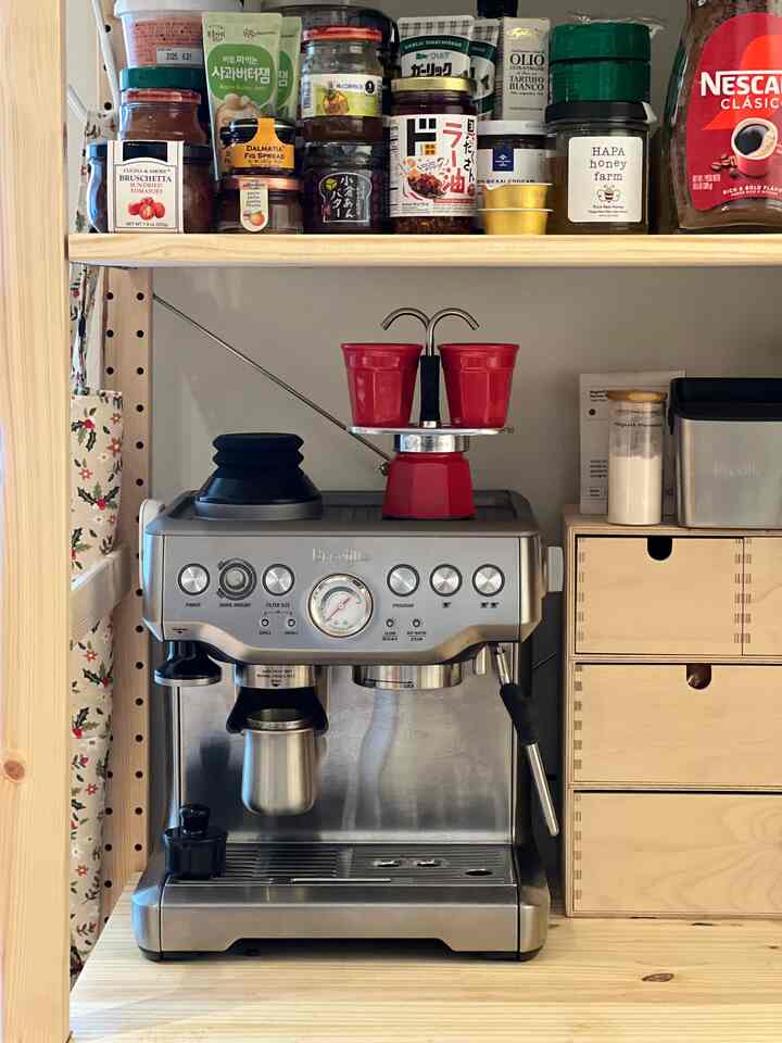 Natural wood-tone shelving and a coffee machine featured in a home cafe kitchen space