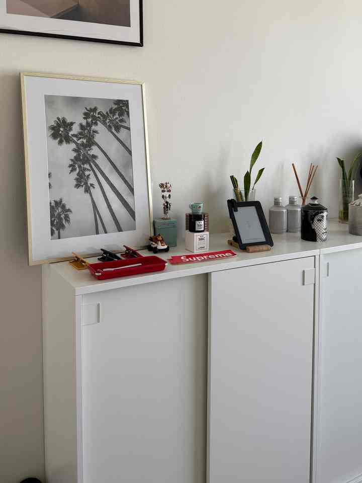 White-toned shoe cabinet with black-and-white wall photo and various decorative objects in a modern style space