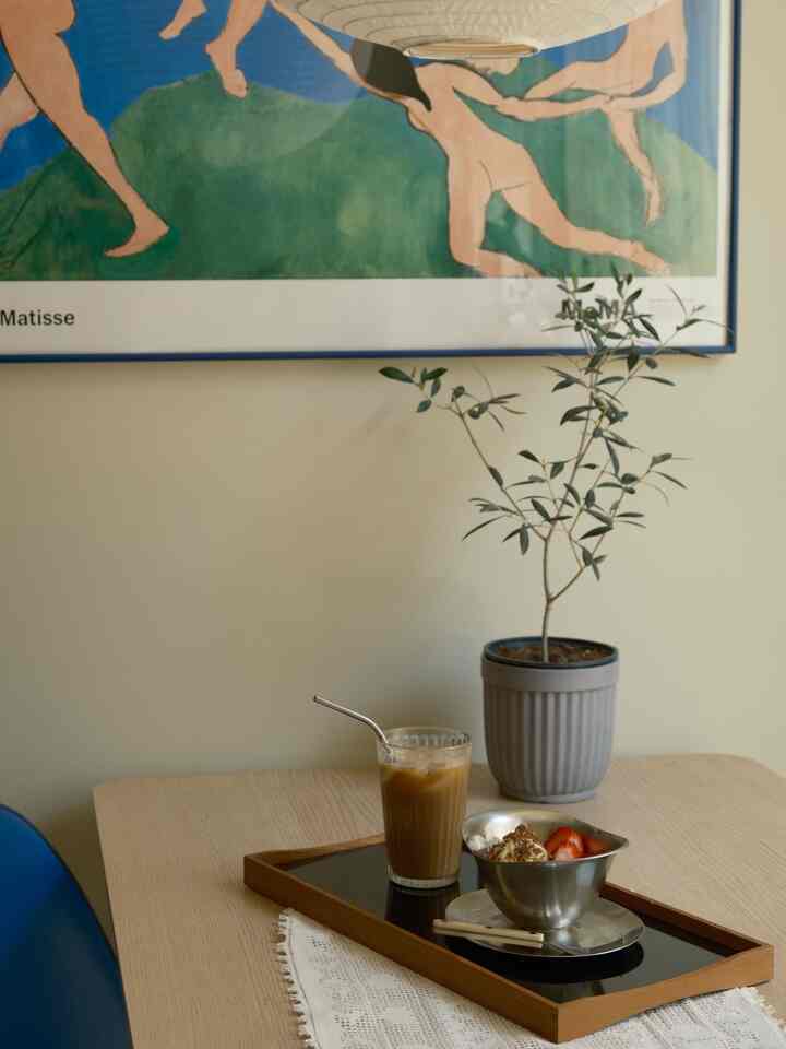 Beige-toned wall and blue chair in cafe style space, featuring glass and dessert on dining table creating cozy home cafe vibe