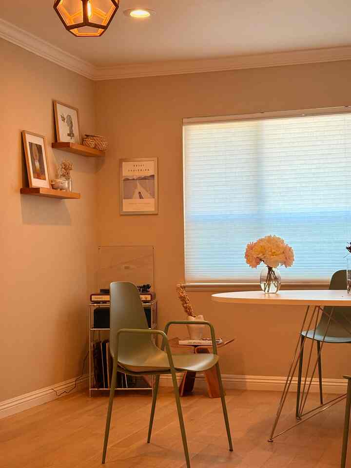 Warm beige-toned dining room featuring a white dining table and green dining chairs with a natural atmosphere