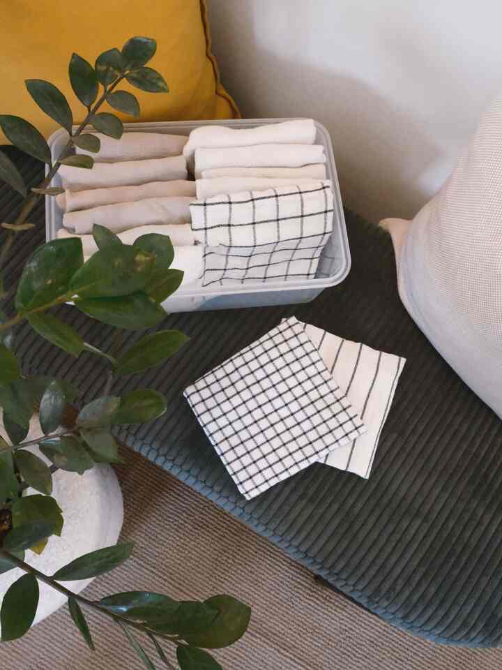 Natural-toned kitchen space featuring neatly folded white towels and cushions with a cozy, organized atmosphere
