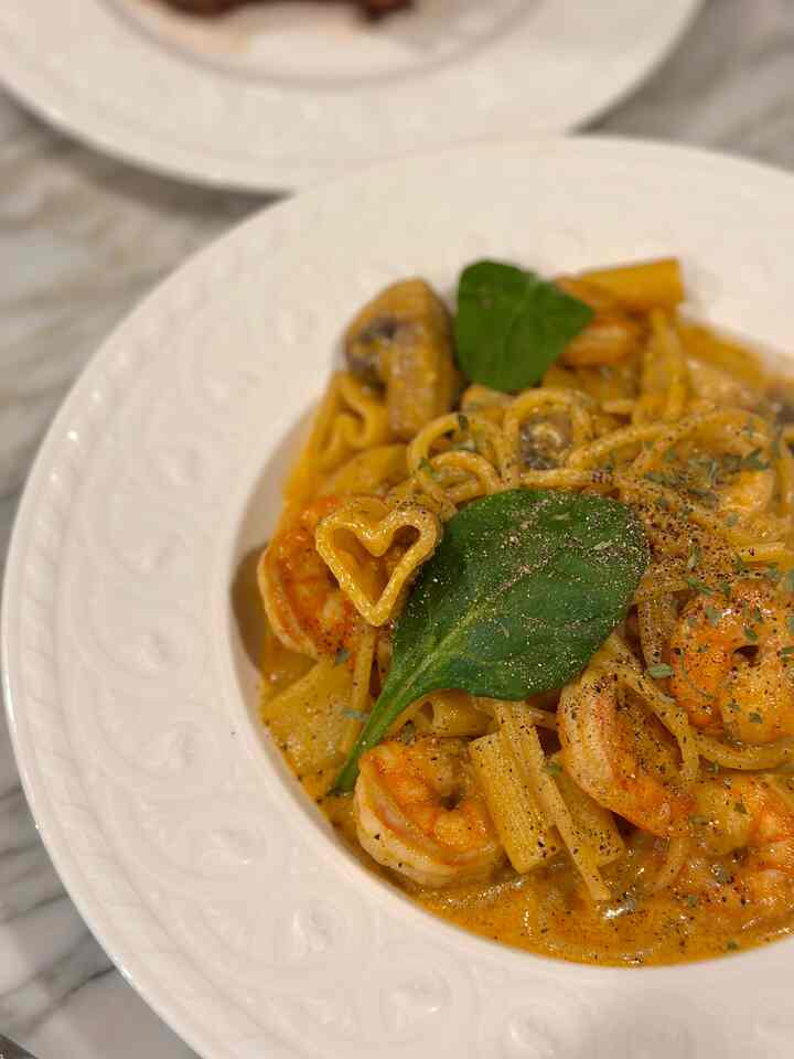 White dining table featuring a plate of shrimp cream pasta emphasizing a cozy dining room setting