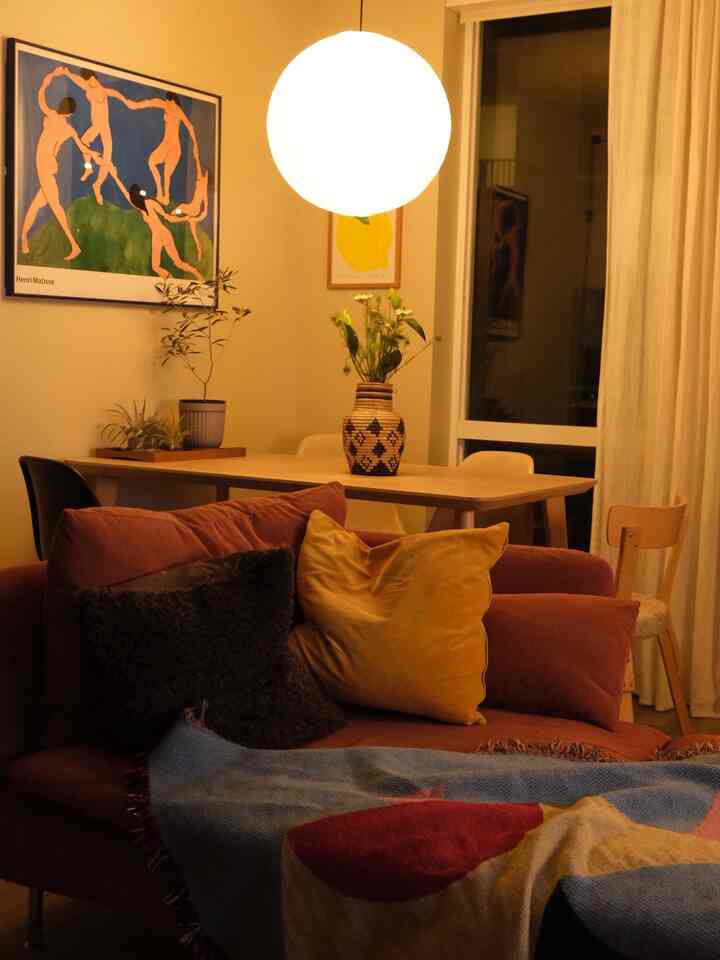 Cozy living room with warm yellow tones and brown hues featuring a sofa and dining table arranged comfortably