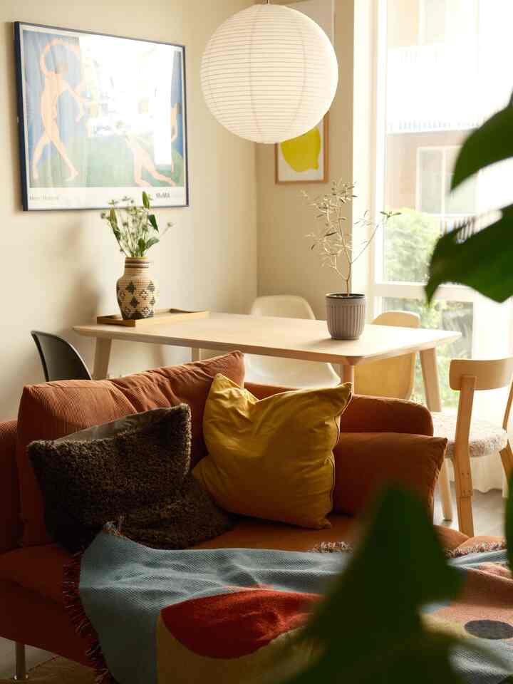 Beige and orange toned dining room featuring a wood dining table and cushion-accented sofa with cozy atmosphere
