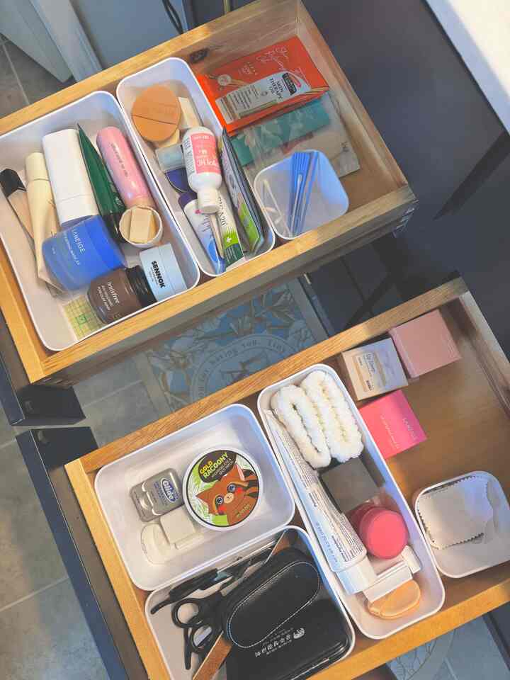Neat bathroom drawer featuring white trays with organized skincare and accessories, showcasing storage ideas