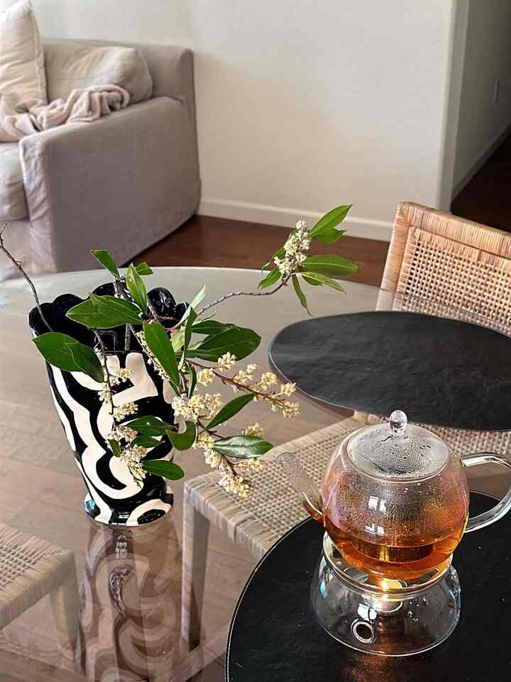 Natural wood tone and beige living room featuring transparent glass teapot and vase on tables, creating a stylish home cafe atmosphere