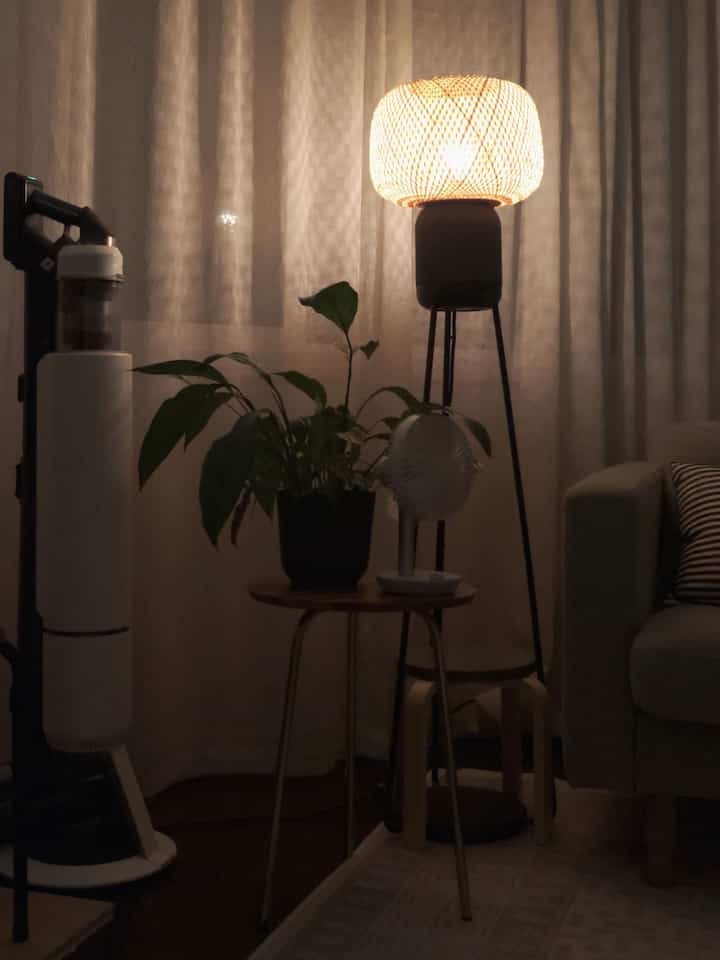 Warm-toned living room corner featuring a gray sofa, wooden side table, and softly glowing floor lamp