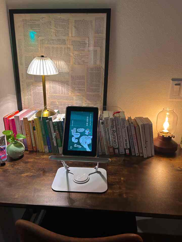 Warm brown wood tone home office space with bookshelf, tablet stand, and framed wall art on cozy desk