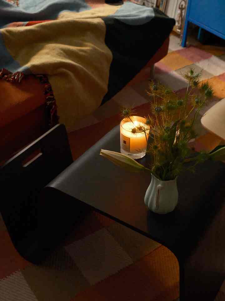 Warm yellow and black toned living room featuring wooden coffee table with lit candle and floral decor, creating a cozy ambience