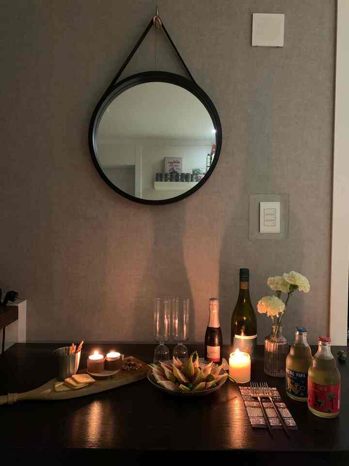 Gray wall and black table dining room space featuring a home bar setup with candle lighting creating cozy night mood