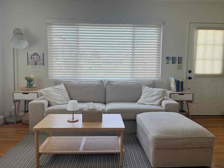 Beige-toned living room featuring beige sofa and ottoman with wooden coffee table, creating a cozy atmosphere