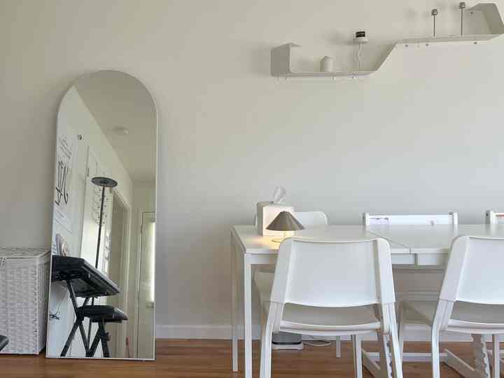 Clean dining room with dominant white and natural wood tones, minimal furniture arrangement creating a spacious feel