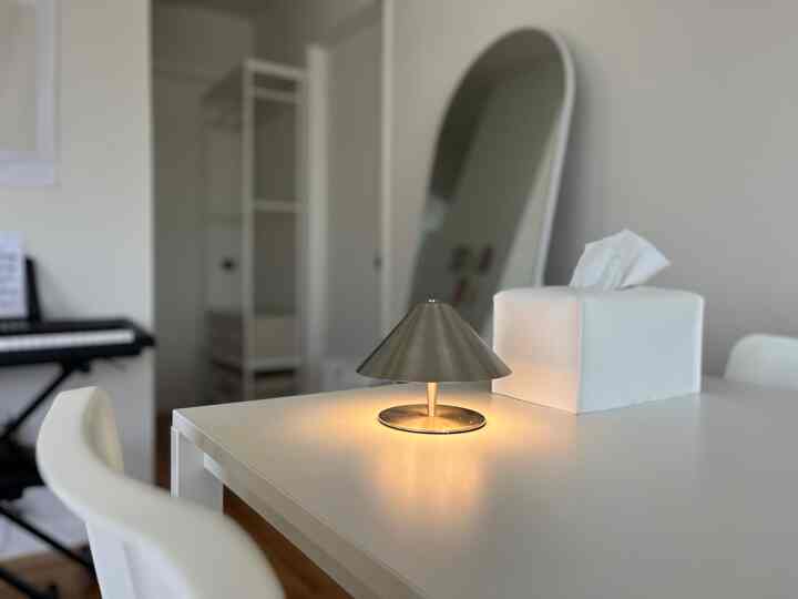 Simple and modern white-toned space featuring a table lamp and tissue box on a central dining table in living room