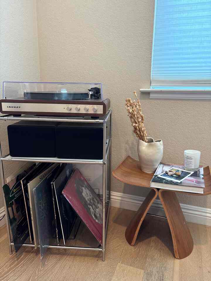 Warm brown wood tones and soft white background in a living room corner featuring a vintage record player and wooden stool in a cozy setting