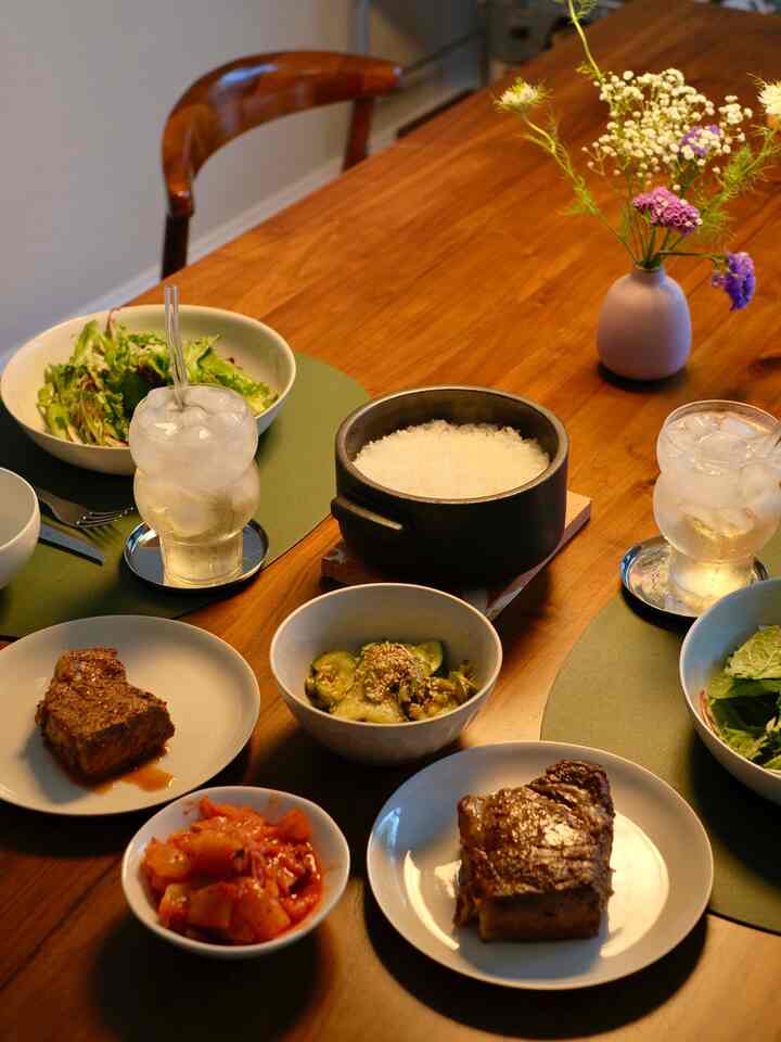 Natural toned dining space featuring a brown wooden table with rice, side dishes, and a flower vase