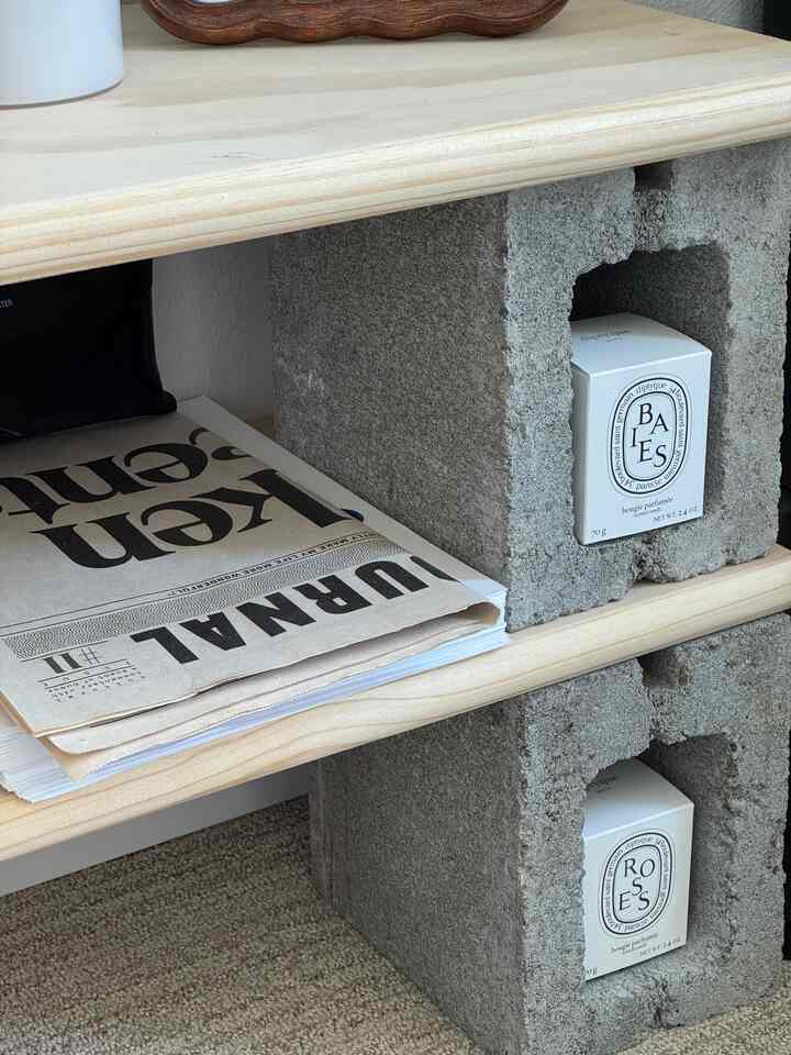 Natural brown wooden shelves supported by gray concrete blocks in a DIY home office storage space, clean and simple atmosphere