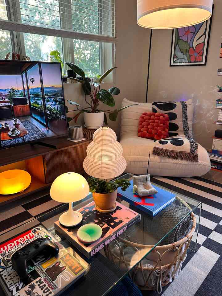 Light gray toned living room featuring a white sofa, glass coffee table, floor lamp, and TV stand creating a cozy modern ambiance